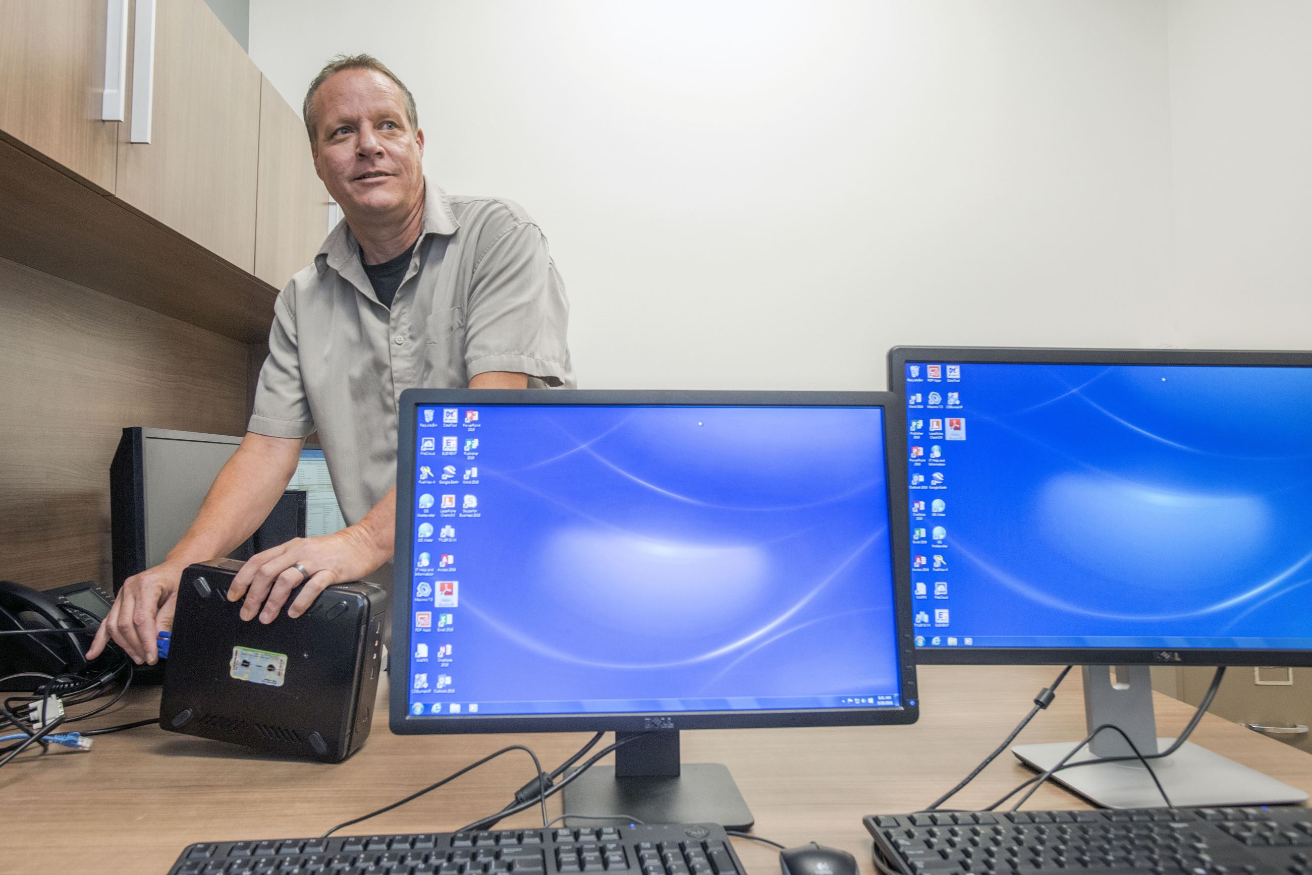 person plugging in a phone with two monitors
